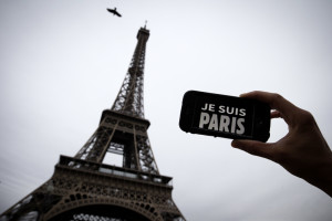 In this illustration picture taken in Paris on November 14, 2015 a person holds aloft a smartphone bearing the message "Je Suis Paris" in front of the Eiffel Tour, following a series of attacks on the city in which at least 128 people were killed.  Islamic State jihadists on Saturday claimed a series of coordinated attacks by gunmen and suicide bombers in Paris that killed at least 128 people in scenes of carnage at a concert hall, restaurants and the national stadium.  AFP PHOTO / JOEL SAGET